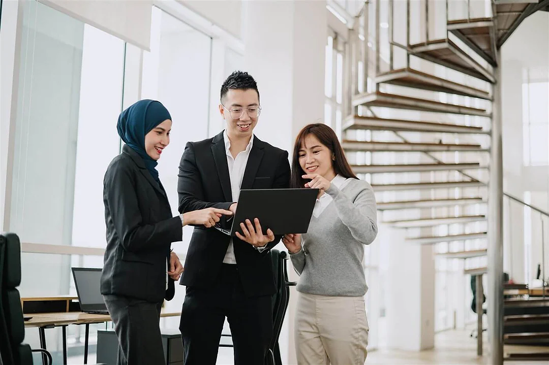 Colleagues reviewing details on a laptop in a modern office